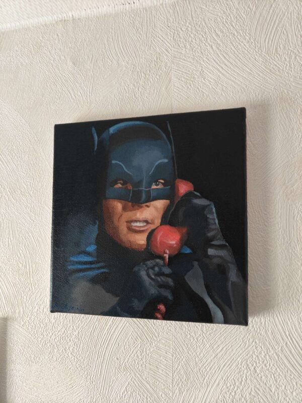 Angled view showing the deep cinematic contrast and the red Batphone on the Adam West original oil painting
