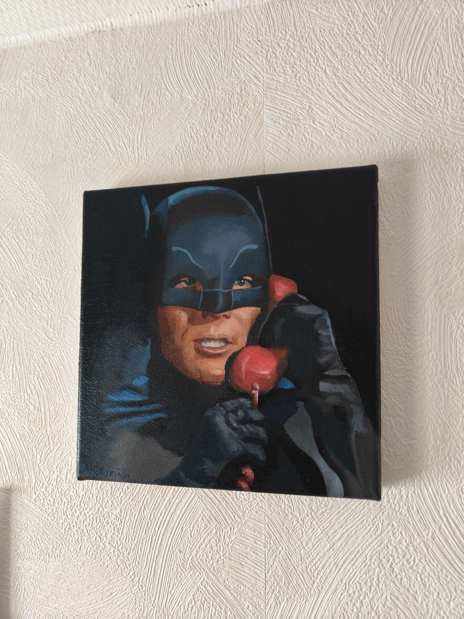Angled view showing the deep cinematic contrast and the red Batphone on the Adam West original oil painting