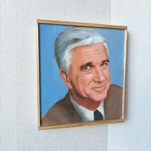 Vasemmalta viistosta kuvattu Oskari Myllymäen alkuperäinen öljyvärimaalaus, joka esittää näyttelijä Leslie Nielseniä Frank Drebinin roolissa. Teos on maalattu puupaneelille ja siinä on vaalea puukehys.