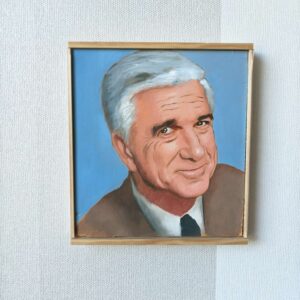 Tiukasti kehyksiin rajattu etukuva Oskari Myllymäen Leslie Nielsen (Frank Drebin) -öljyvärimaalauksesta. Kuva korostaa teoksen sivellintekniikkaa sileällä puupaneelilla.