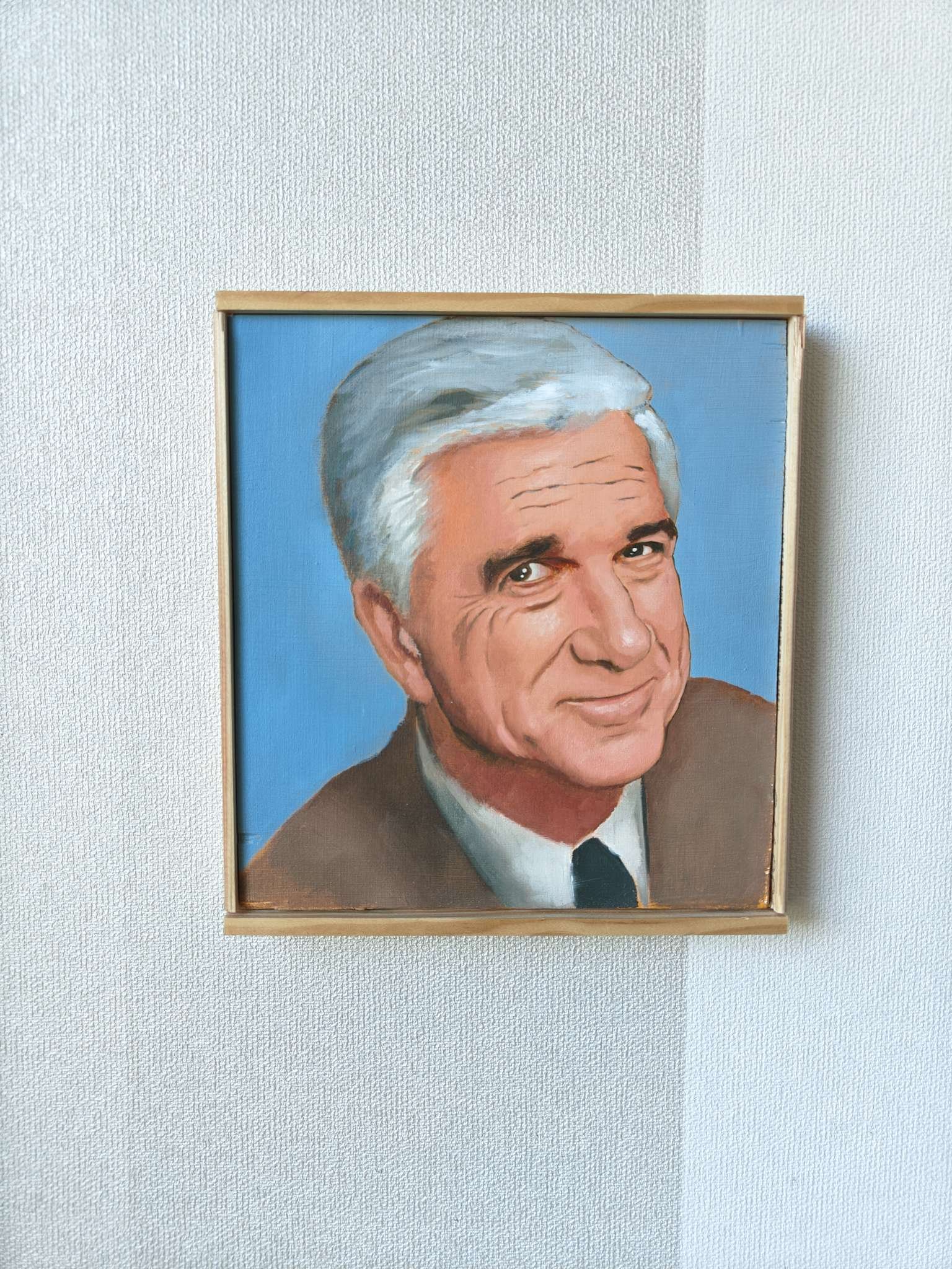 Tiukasti kehyksiin rajattu etukuva Oskari Myllymäen Leslie Nielsen (Frank Drebin) -öljyvärimaalauksesta. Kuva korostaa teoksen sivellintekniikkaa sileällä puupaneelilla.